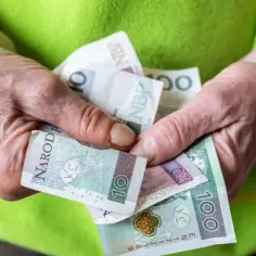 Dłonie trzymają polskie banknoty: 10, 20 i 100 zł. Zastanawiasz się, ile wynosi renta?