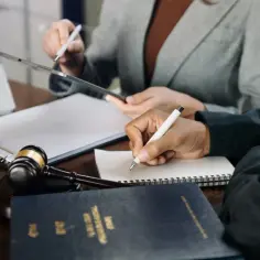 Prawnicy analizują dokumenty i notują kluczowe informacje. Na biurku leży młotek sędziowski, laptop i opasłe tomy, sugerujące sprawę z artykułu 288 kk.