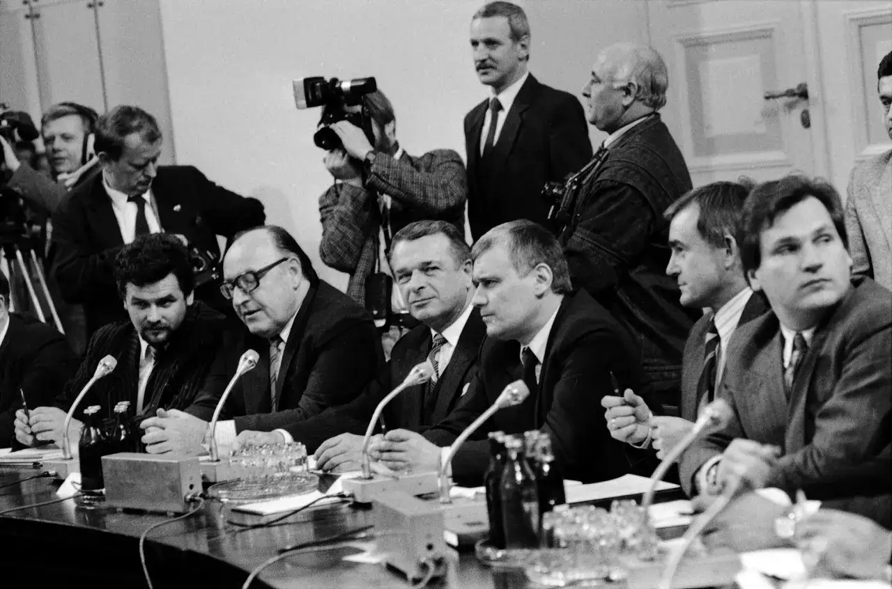 Mężczyźni przy stole, kamery, mikrofony – to obraz kluczowego momentu, jakim był upadek komunizmu w Polsce.