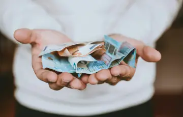 Dłonie trzymające banknoty euro. Pieniądze symbolizują wolność i możliwości, które często wiążą się z posiadaniem obywatelstwa.